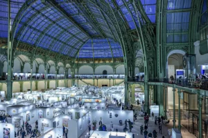 Art Capital Paris, 2026, salon international d'art, peinture, sculpture, grand palais, paris, vue de la verrière du grand palais bleu nuit, prise à la tombée de la nuit, les stands visibles en blanc, en dessous, visiteurs en balade dans le salon