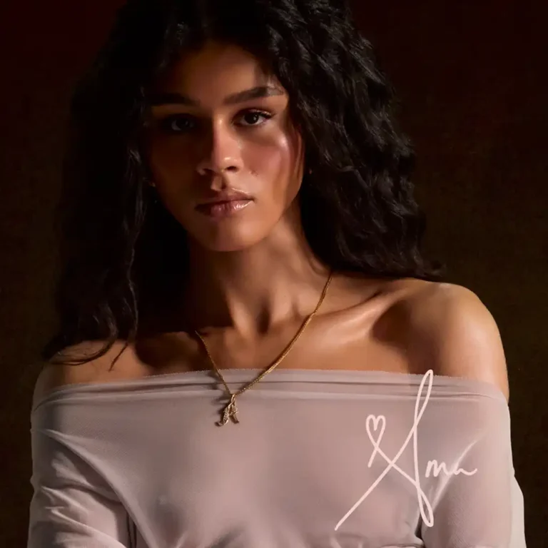 Ama Lou livre "AMA", en 2026 Ama Lou livre AMA, en 2026, pochette de l'album AMA, Ama Lou, photo en buste dans un crop mousseline beige, légèrement translucide, dur fond sombre.