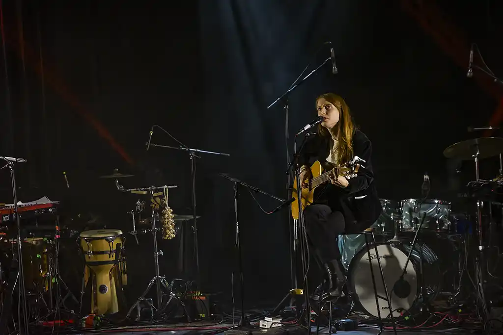 Aure, aux 3 Baudets - MaMA 2025 + Live 2026, Vue d'ensemble de la scène lors du concert d'Aure. Mama 2025, La chanteuse est entourée de son setup minimaliste : batterie, percussions et micros, dans une atmosphère épurée
